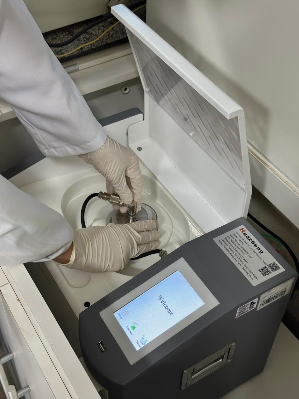 Técnica da BREDA posicionando os eletrodos no copo de ensaio do medidor de rigidez dielétrica